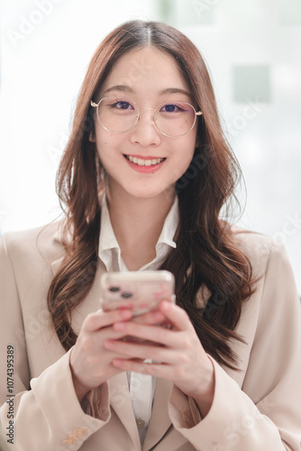 Professional woman engages with smartphone while smiling in a modern office setting