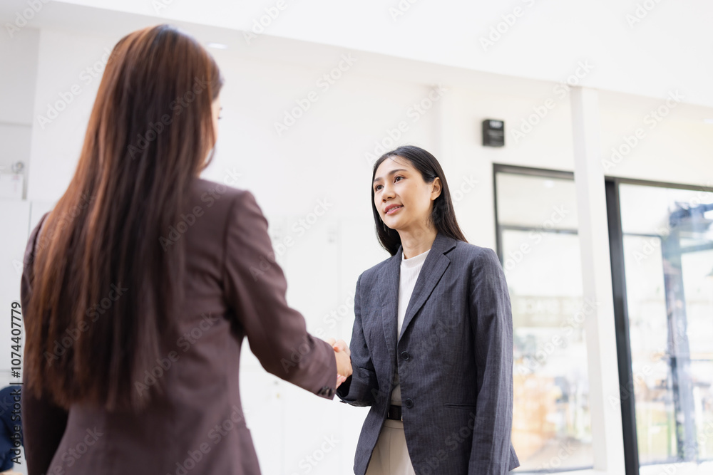 Two young Asian female making handshake inside at office workplace, partner, greeting, businesswomen handshake. Two young Asian female making handshake inside at office workplace, partner, greeting, businesswomen handshake.
