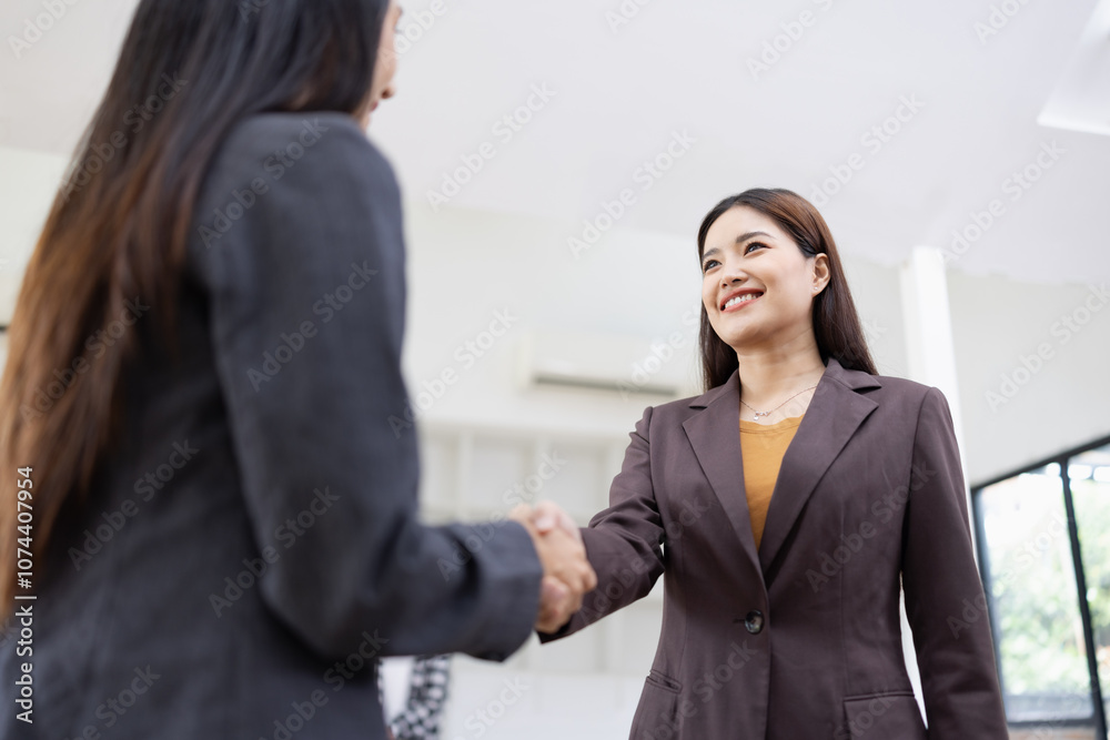 Two young Asian female making handshake inside at office workplace, partner, greeting, businesswomen handshake. Two young Asian female making handshake inside at office workplace, partner, greeting, businesswomen handshake.