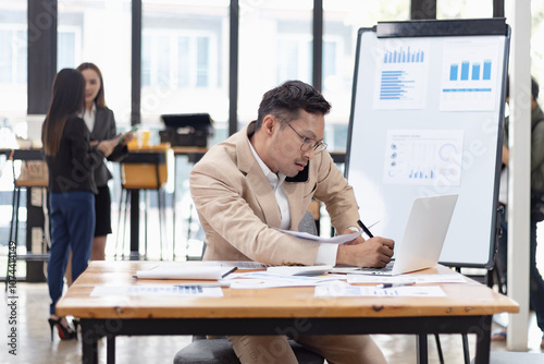 Happy asian businessman working with business financing accounting banking and laptop with finances analysis report at desk in office. 