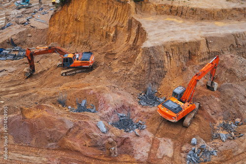 Excavators dig the ground in the foundation pit of a building on a construction site. View from above photo