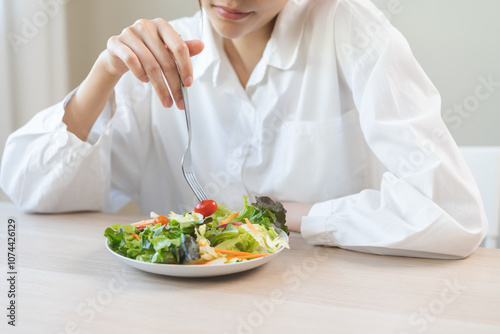 Diet in bored face, unhappy beautiful asian young woman, girl on dieting, holding fork at tomato on salad plate, dislike or tired with eat fresh vegetables. Nutrition of clean, healthy food good taste photo