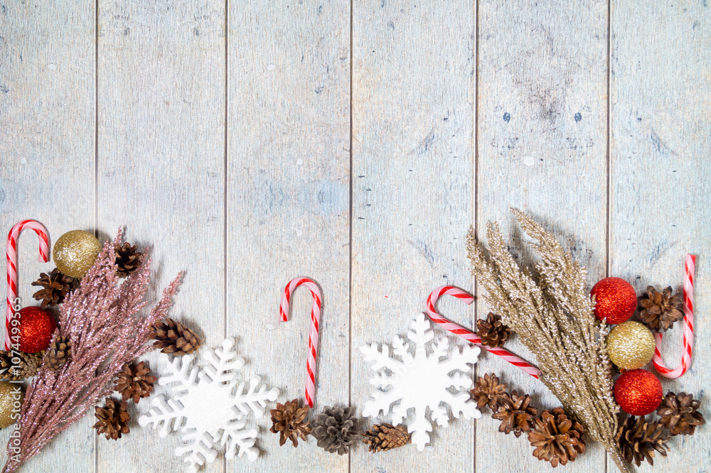 Naklejka premium Christmas decorations on a wooden background: Christmas tree balls, branches, snowflakes and candy canes, top view, copyspace