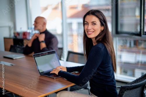 Confident businesswoman sitting at desk in a modern office and working on her laptop