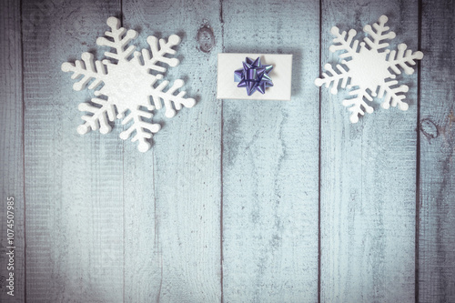 White decorative snowflakes and giftbox on blue wooden background, copy space