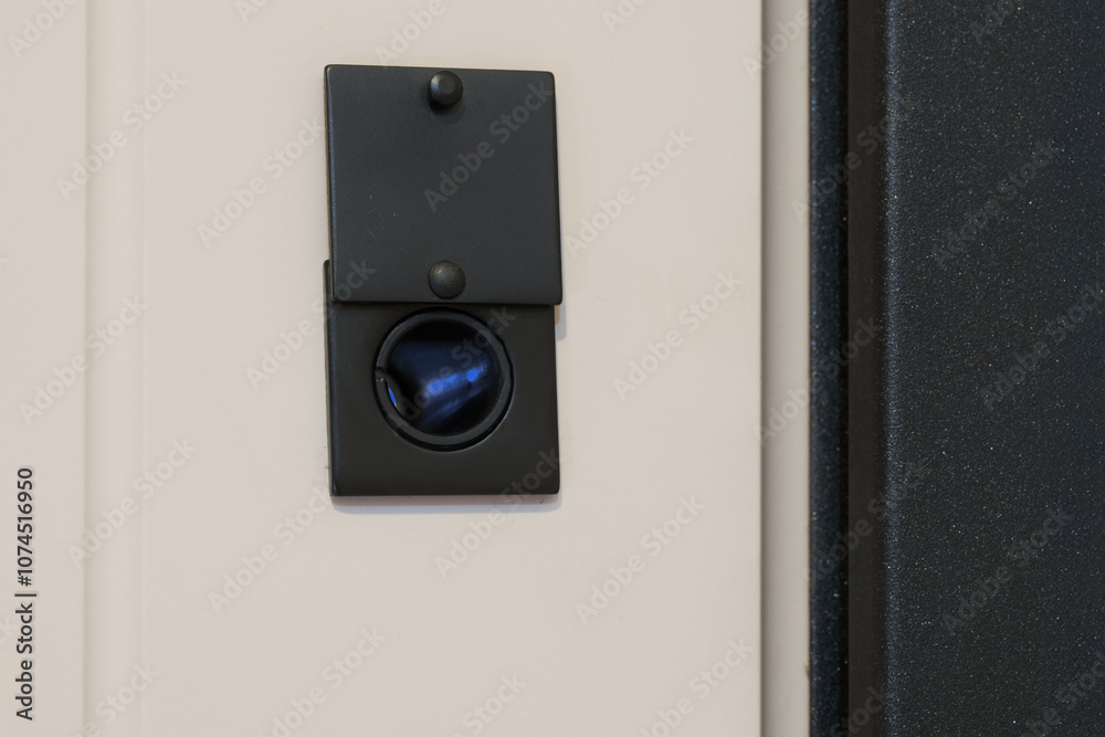 Black square door peephole with security bolt on armored metal entrance door. View from inside the room. Privacy and security. Peeping and surveillance. Copy space. Photo Black square door peephole with security bolt on armored metal entrance door. View from inside the room. Privacy and security. Peeping and surveillance. Copy space. Photo