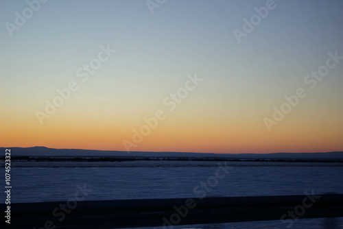 Sunset on the frozen lake in the winter. Beautiful winter landscape.