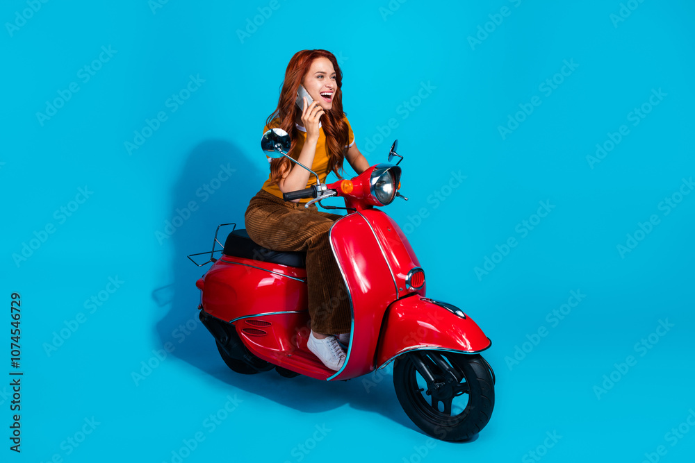 Photo of cheerful positive woman wear stylish clothes drive motorcycle speak phone isolated on blue color background Photo of cheerful positive woman wear stylish clothes drive motorcycle speak phone isolated on blue color background