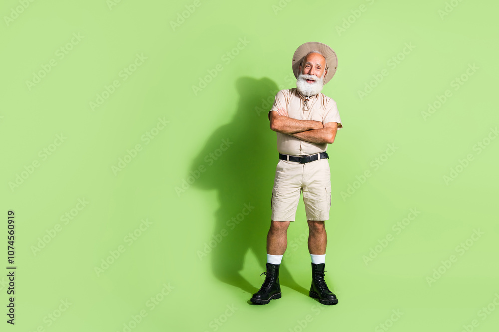 Photo of safari guide eco tourist senior man standing smiling with crossed arms isolated green color background Photo of safari guide eco tourist senior man standing smiling with crossed arms isolated green color background