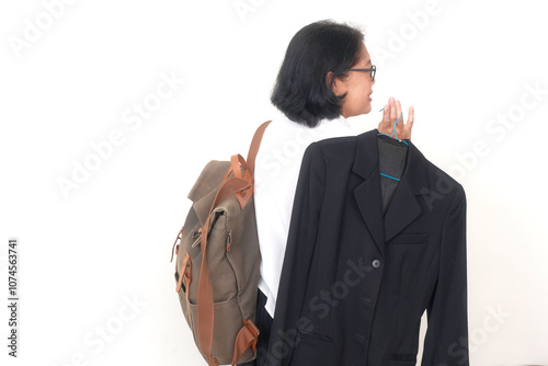 Rear view: A middle-aged woman carrying a backpack and dark blazer with a hanger on her shoulder photo