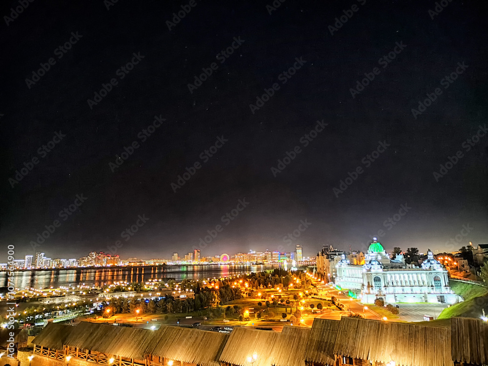 Fototapeta premium Night view of Kazan's illuminated skyline overlooking the river and historical buildings in Tatarstan, Russia