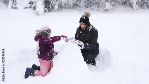 Mother and daughter enjoy a snowy day together, creating memories and sharing winter joy in a beautiful landscape