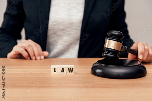 close up of Judge holding justice gavel next to wooden blocks with LAW Text on Desk photo