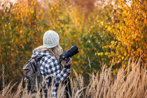 Woman photographer with camera exploring autumn nature. Outdoor leisure activity photo