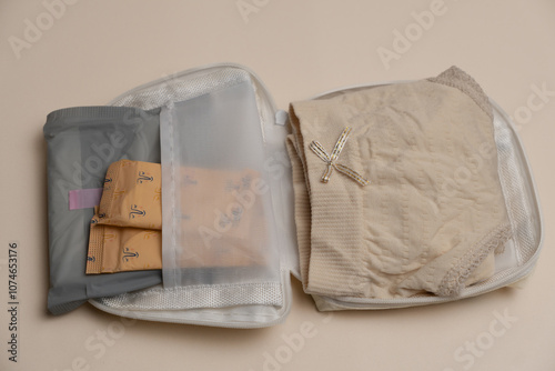 Compact pouch with sanitary products and beige underwear inside