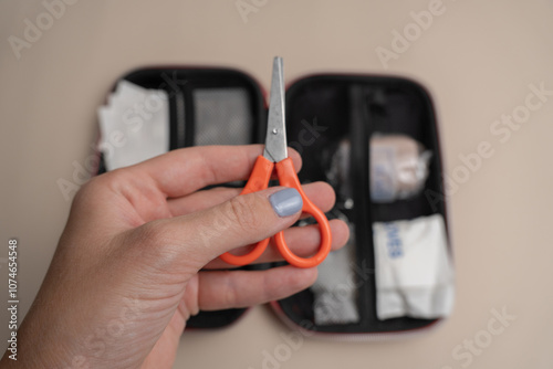 Orange-handled scissors from a first aid kit held in hand, ready for emergency situations photo