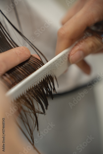 A male hairdresser cutting a long dark woman's hair. Hair beauty salon.