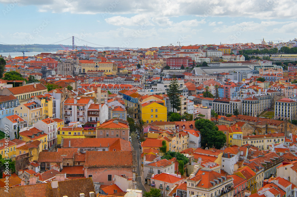 Obraz premium Suspension bridge Ponte 25 de Abril in Lisbon, Portugal. View of colourful facades and The 25th April Bridge over river Tajo. Travel summer photography.