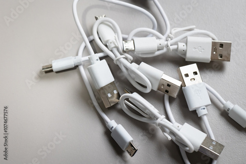 A collection of white USB-A, type A and micro-usb short cables, with some tied up with a twist cable tie. 