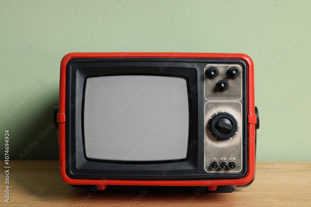 Retro tv set on wooden shelf against green wall Retro tv set on wooden shelf against green wall