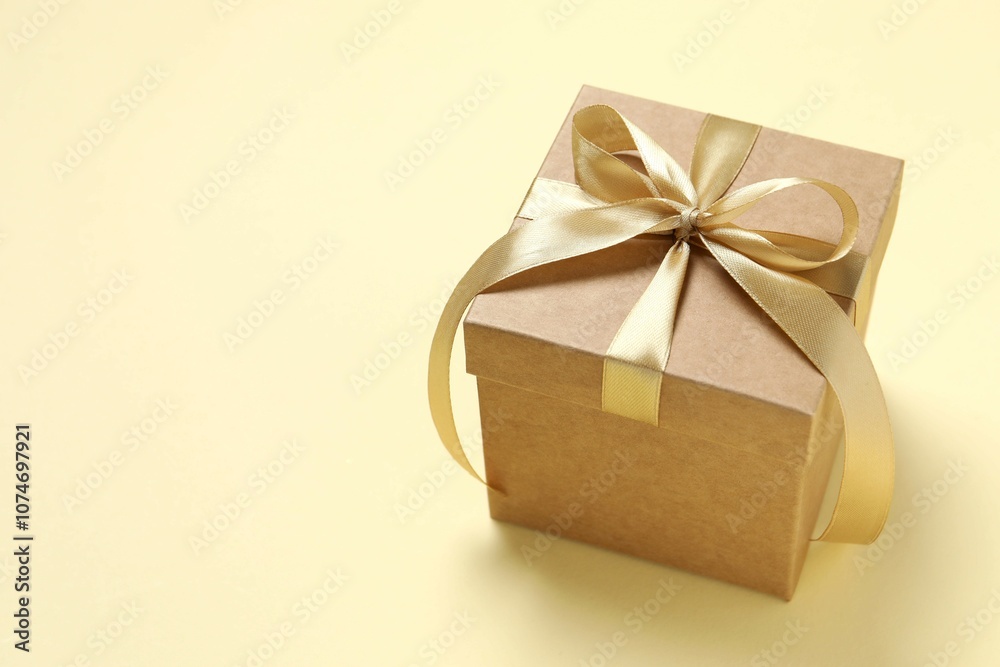 Obraz premium Beautiful gift box tied with golden bow on color background 