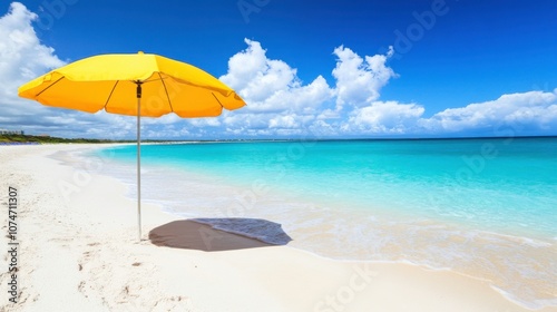 Sunny beach with a yellow umbrella by the water.