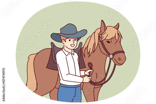 Cowboy boy is standing next to horse caring for stallion and wanting to become professional jockey and race. Schoolboy wearing texas ranger hat near horse for ride or competition at racetrack