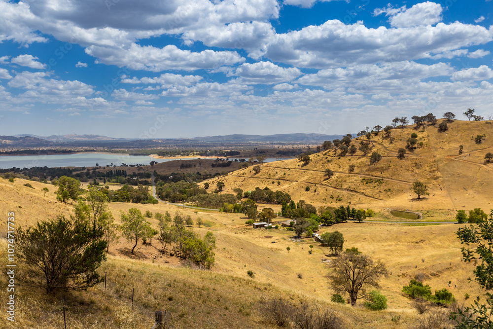 Stunning view from Kurrajong Gap Lookout showcasing golden hills, trees and meadows and serene waterway under a cloudy sky, Victoria, Australia Stunning view from Kurrajong Gap Lookout showcasing golden hills, trees and meadows and serene waterway under a cloudy sky, Victoria, Australia