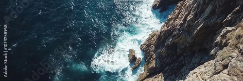 Drone shot of dramatic cliffside overlooking the ocean, with waves crashing against the rocks below