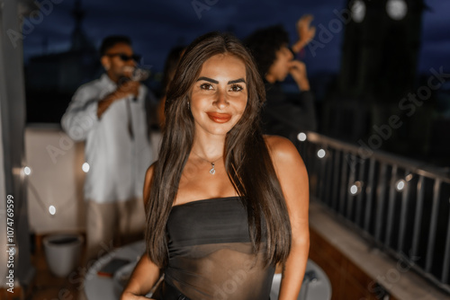 Beauty seductive woman dancing during night roof party withl friends photo