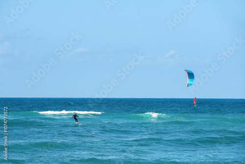 Kitesurfers enjoy a sunny day on the waves at a beautiful coastal location under a clear blue sky