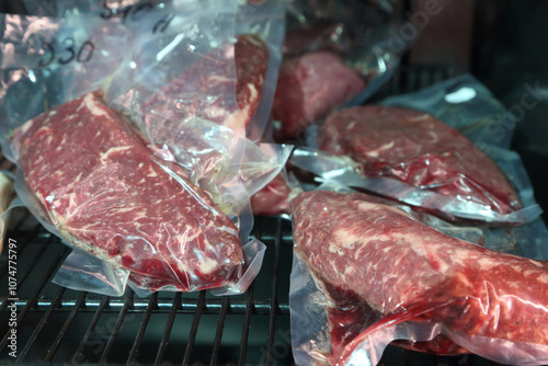 Beef steaks are kept in a special refrigerator before being cooked. Steaks in airtight packaging in the refrigerator. Maturing steaks before cooking. Beef steaks in refrigerator.