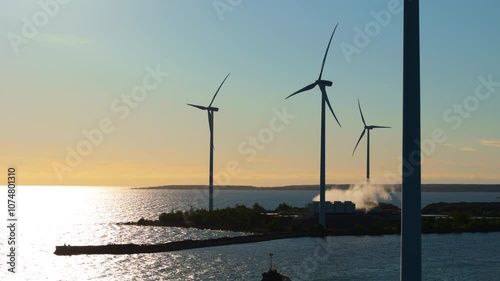 Rotating wind turbines against vivid sunrise sky on Scandinavian coast, drone photo