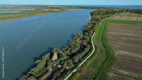 aerial reveal of the Nicesolo canal fishing community using traditional Venetian reed construction called Casoni di Caorle, Caorle, Italy photo