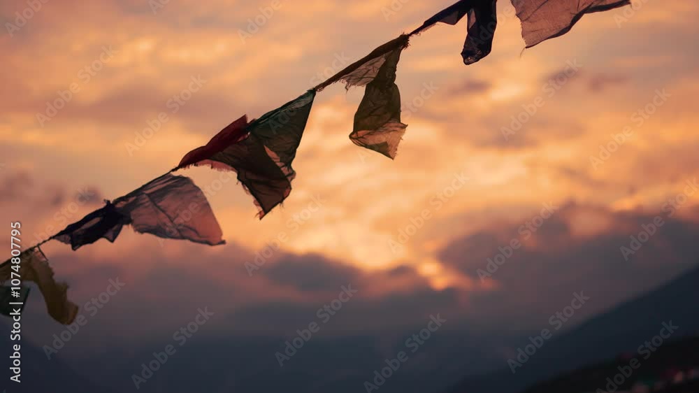 4K Slow motion shot of prayer flags waving in the wind in front of snowy Himalayan mountain peaks covered by clouds during the sunset at Khangsar village in Lahaul valley, Himachal Pradesh, India.