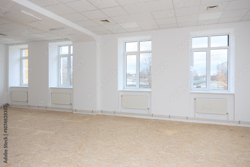 Fototapeta premium Spacious renovated room with large windows and white walls, natural light filling the space