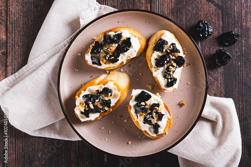 Close up of delicious toasts with ricotta and prunes on a plate on the table web banner top view photo