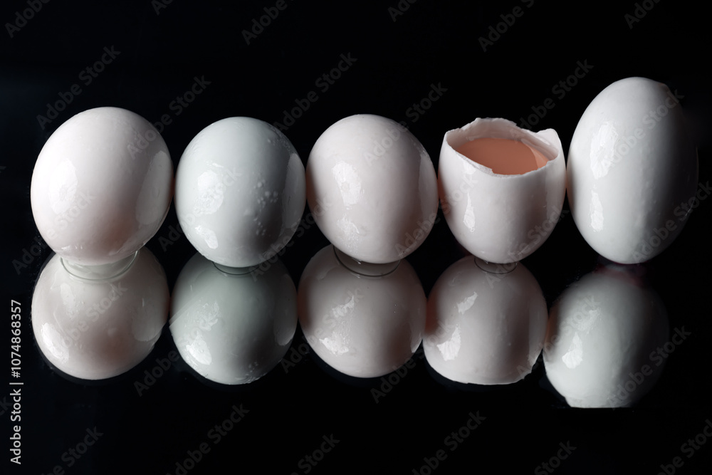 The reflection of Five raw duck eggs are sitting in a row with an egg broken in half showing the yolk and white egg on black background. use it as your Wallpaper, Poster and Copy space,Selective focus