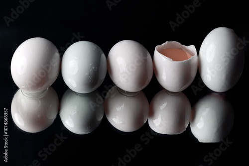 Obraz na płótnie The reflection of Five raw duck eggs are sitting in a row with an egg broken in half showing the yolk and white egg on black background. use it as your Wallpaper, Poster and Copy space,Selective focus w salonie