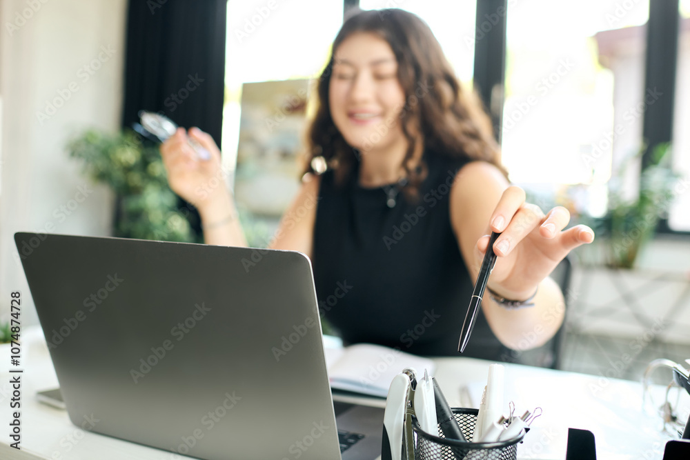 A cheerful young plus size woman with long curly hair interacts with her laptop, immersed in her work while smiling. A cheerful young plus size woman with long curly hair interacts with her laptop, immersed in her work while smiling.