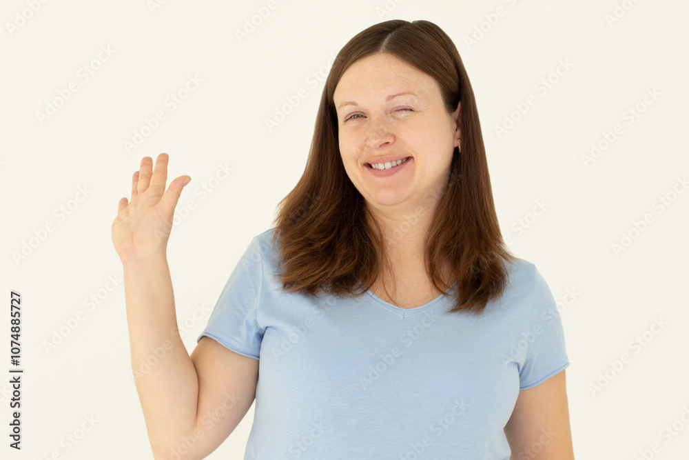 Cheerful friendly girl saying hello, winking and smiling, waving hand at camera, say hi and greet you, standing against white background Cheerful friendly girl saying hello, winking and smiling, waving hand at camera, say hi and greet you, standing against white background