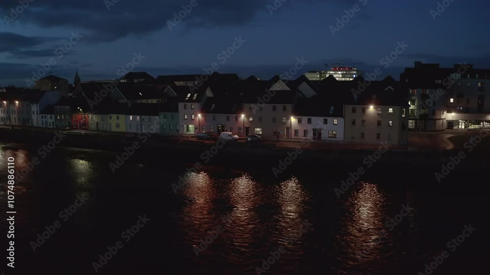 Aerial orbit of the iconic Long Walk in Galway at night, showcasing light reflections on the water in a stunning establishing shot Aerial orbit of the iconic Long Walk in Galway at night, showcasing light reflections on the water in a stunning establishing shot