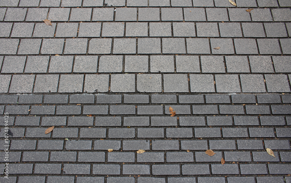 Texture of square paving tile. Pattern of gray tiles in the street. Concrete pavers with autumnal leaves close up background. Texture of square paving tile. Pattern of gray tiles in the street. Concrete pavers with autumnal leaves close up background.