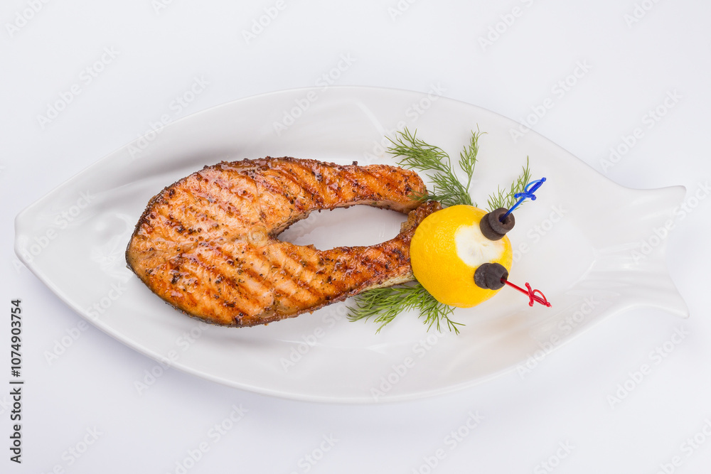 grilled fish steak on the white plate decorated with lemon. top view. delicious keto diet