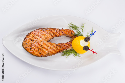 Obraz na płótnie grilled fish steak on the white plate decorated with lemon. top view. delicious keto diet w salonie