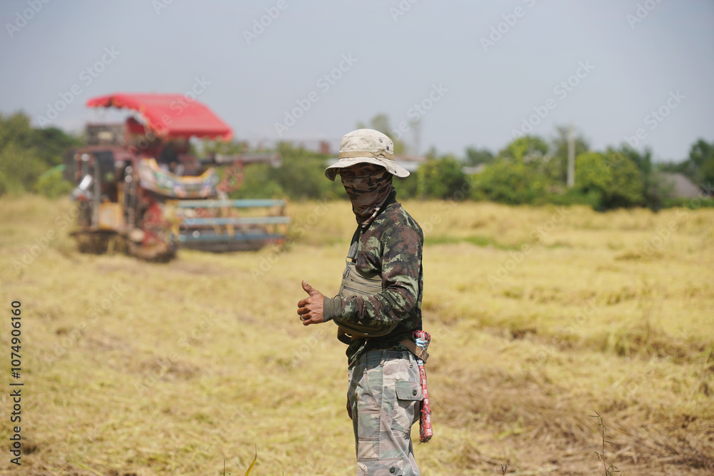 Male farmer standing and giving a thumbs up Rice harvester behind the scenes in harvest season