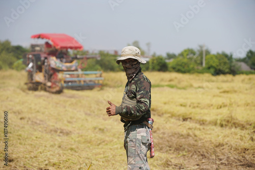 Male farmer standing and giving a thumbs up Rice harvester behind the scenes in harvest season