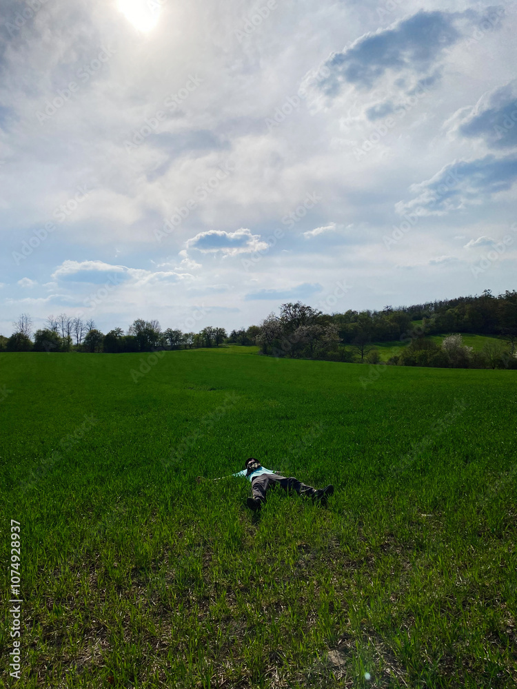 Person relaxing in a peaceful green meadow under a sunny sky Person relaxing in a peaceful green meadow under a sunny sky