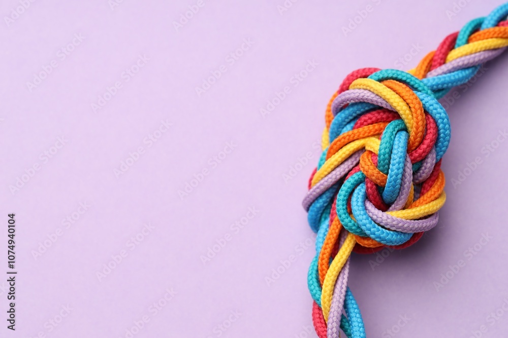 Colorful ropes tied in knot on lilac background, closeup with space for text. Unity concept Colorful ropes tied in knot on lilac background, closeup with space for text. Unity concept