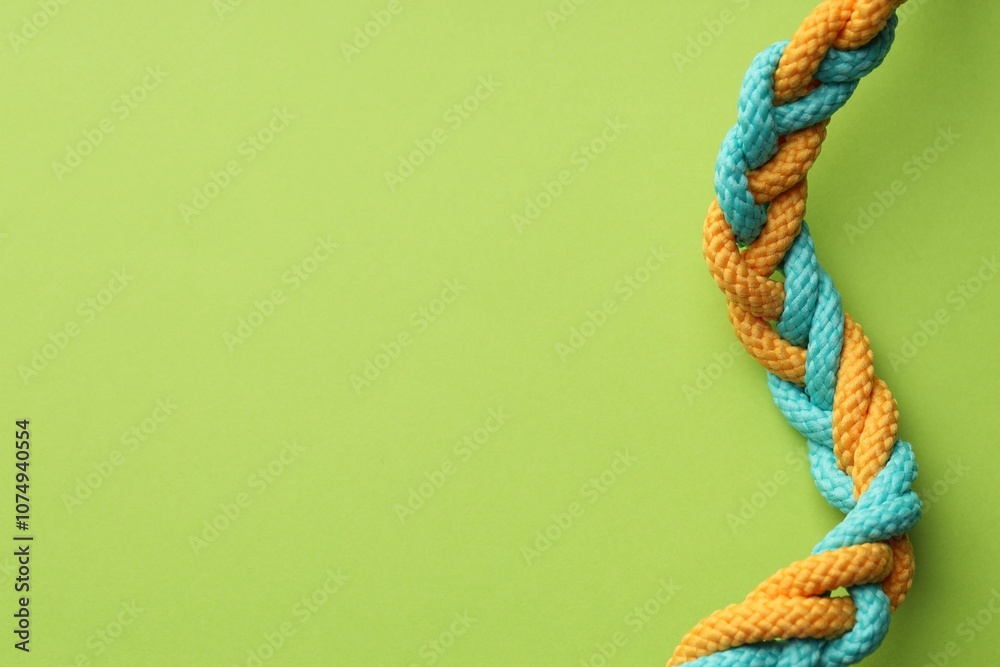 Colorful ropes tied together on light green background, top view and space for text. Unity concept Colorful ropes tied together on light green background, top view and space for text. Unity concept